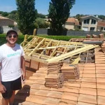 Un employé de BBC Aquitaine en train de poser les tuiles sur la toiture d'une maison individuelle.